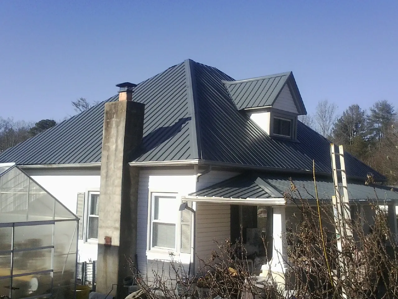 Dark blue standing seam metal roof on a white farmhouse with dormer — Slate & Tile Roof Repair by Roofing Brothers in Murtaugh