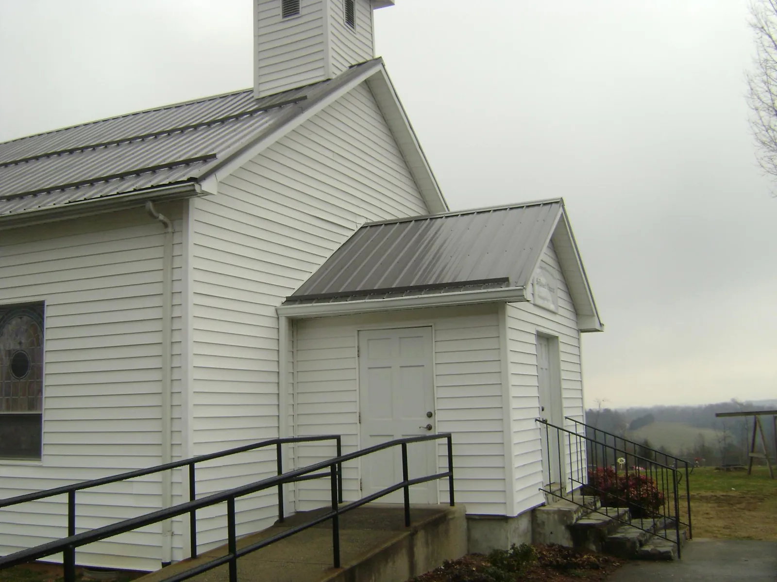 Gray metal roof on a white clapboard church with a steeple in Murtaugh