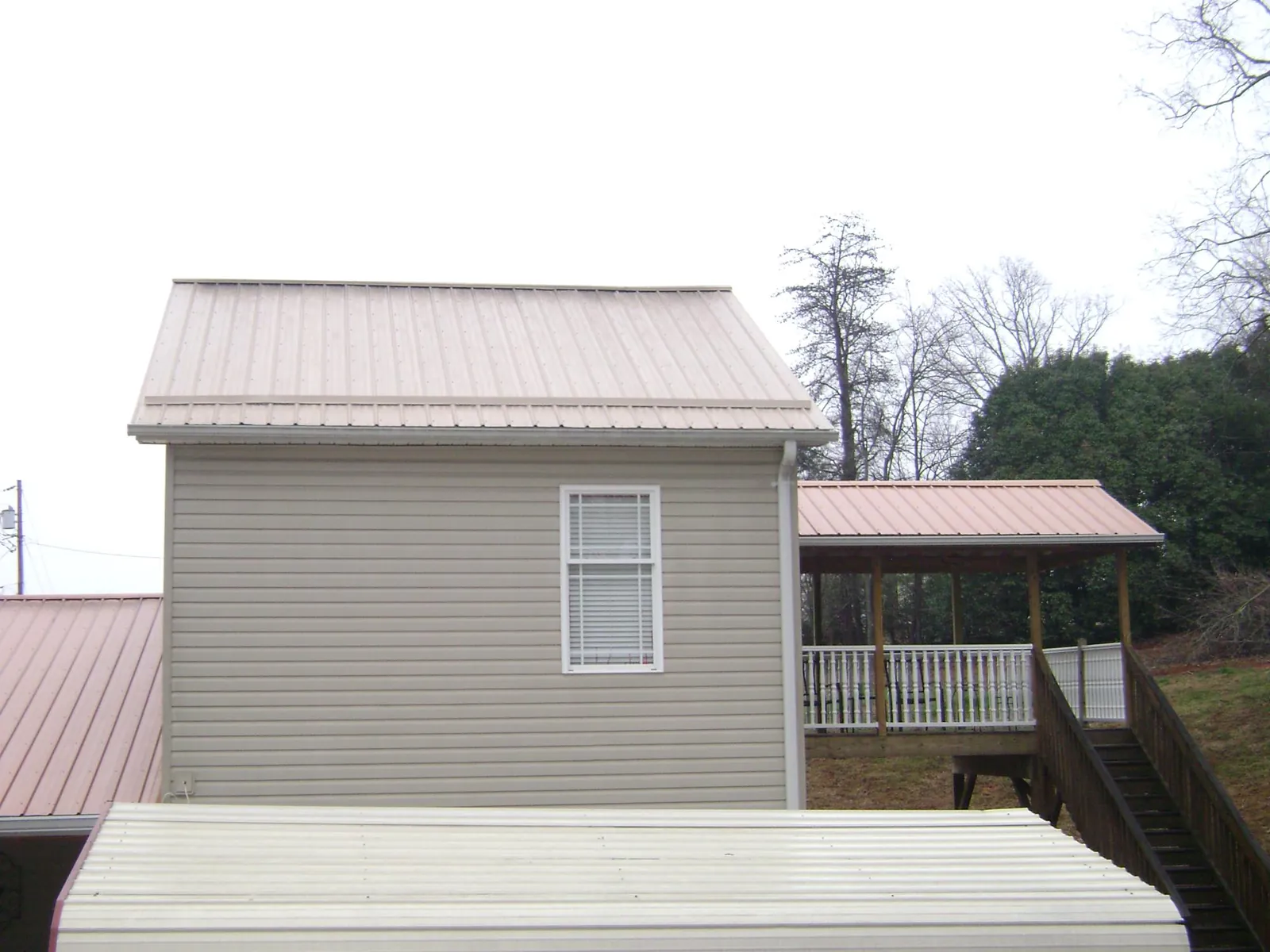 Tan metal roofs on a two story addition and attached porch, from a Roof Replacement job in Murtaugh