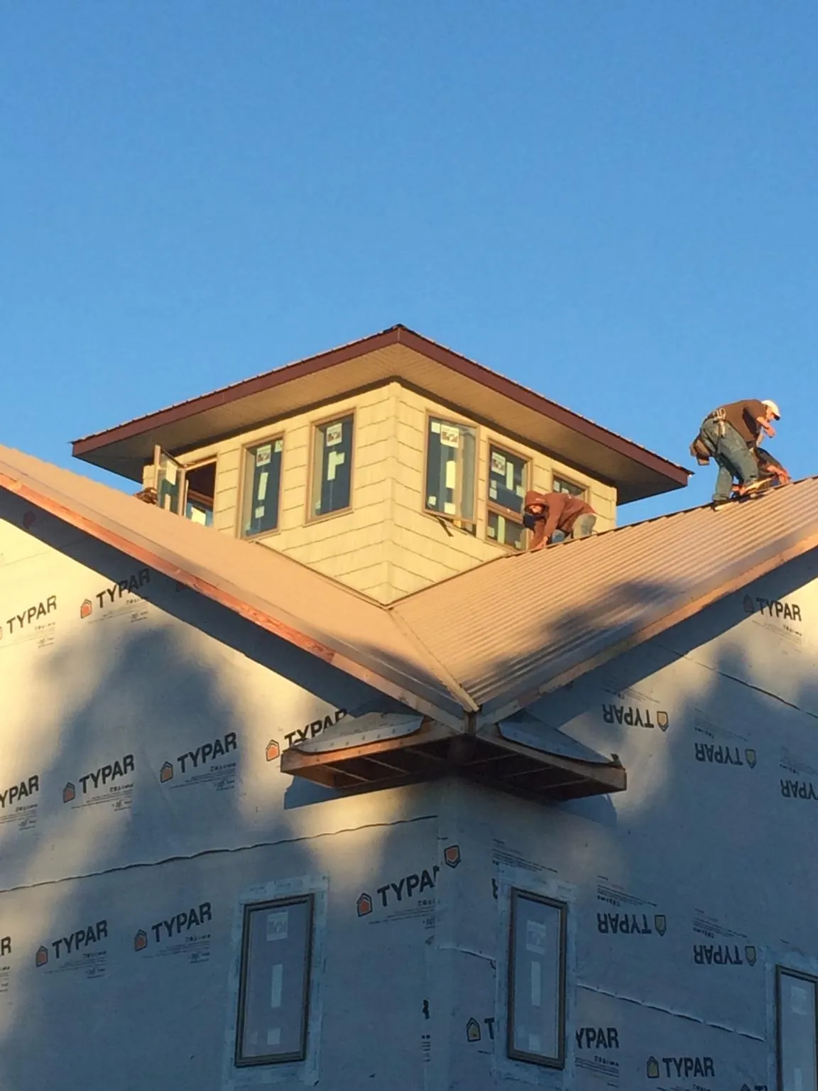 Roofers working around a rooftop cupola on a new metal roof at sunset — Roof Waterproofing in Murtaugh by Roofing Brothers